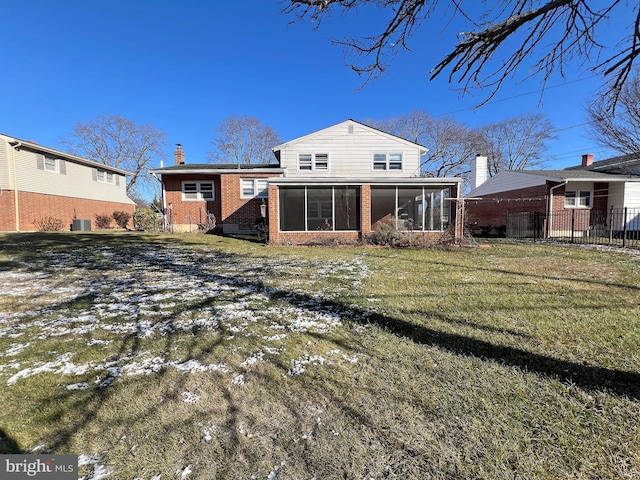 back of property with a sunroom, a lawn, and central AC