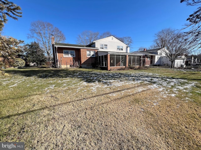 rear view of property featuring a lawn and a sunroom