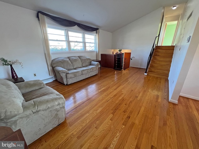 living room with light hardwood / wood-style flooring, vaulted ceiling, and a baseboard heating unit