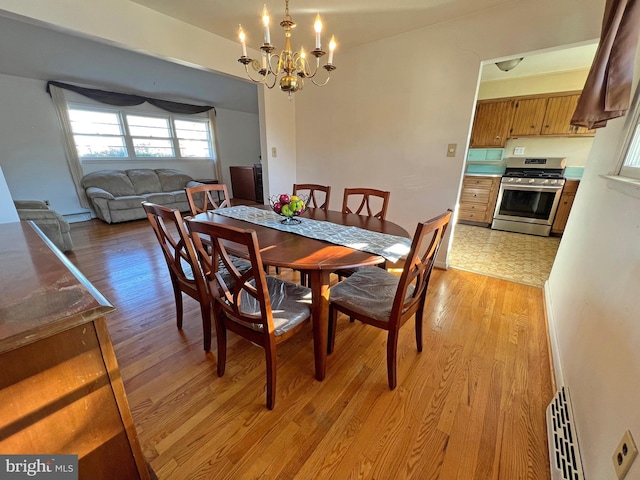 dining space with light wood-type flooring and a notable chandelier