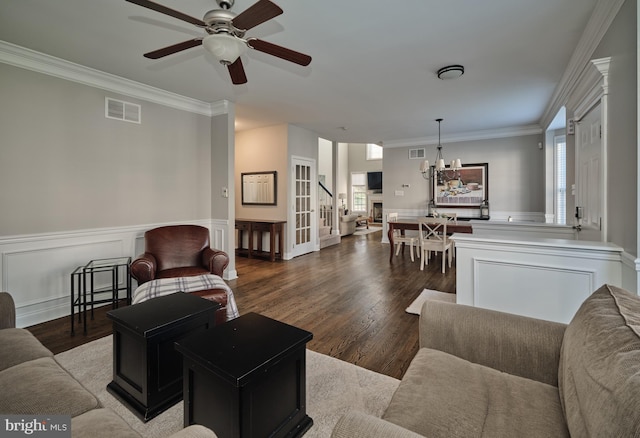 living room with ceiling fan with notable chandelier, ornamental molding, and light hardwood / wood-style flooring