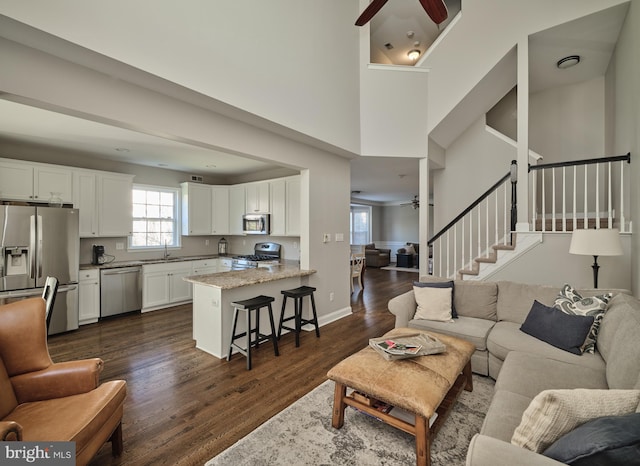 living room featuring dark hardwood / wood-style flooring, ceiling fan, and sink