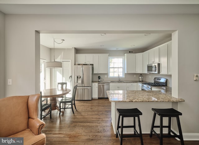 kitchen featuring sink, kitchen peninsula, hanging light fixtures, white cabinetry, and stainless steel appliances