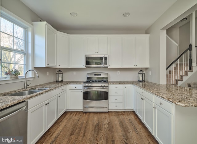 kitchen with kitchen peninsula, white cabinetry, sink, and stainless steel appliances