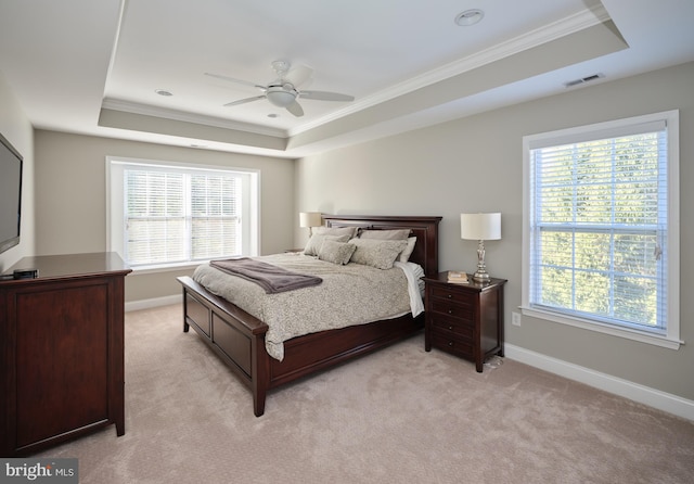 carpeted bedroom featuring a tray ceiling, ceiling fan, and crown molding