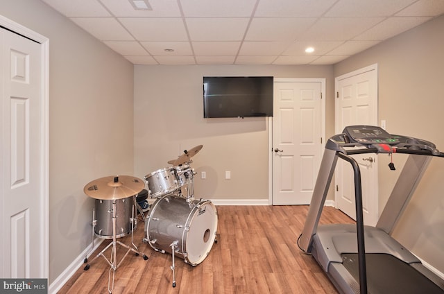 workout room featuring a paneled ceiling and light hardwood / wood-style flooring