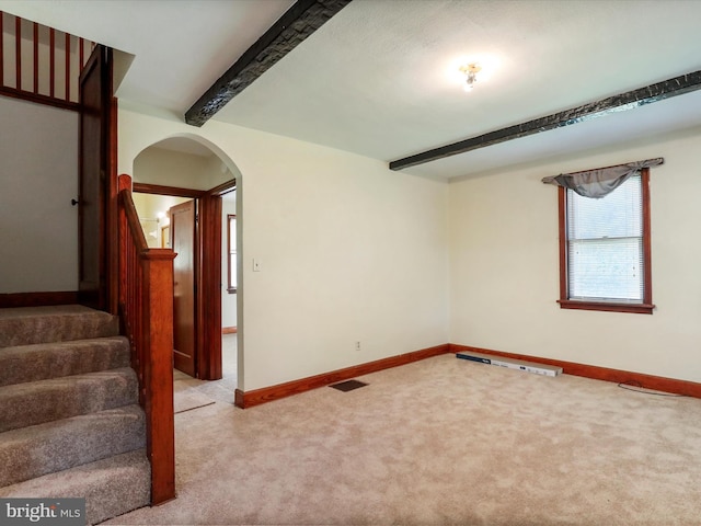 carpeted spare room with beam ceiling