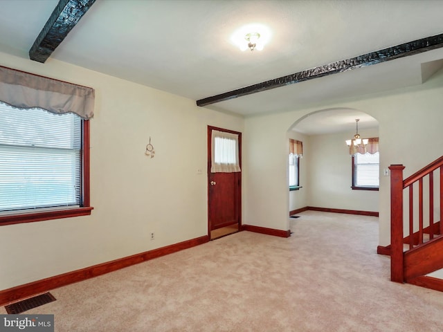 entrance foyer with light carpet, beamed ceiling, and an inviting chandelier