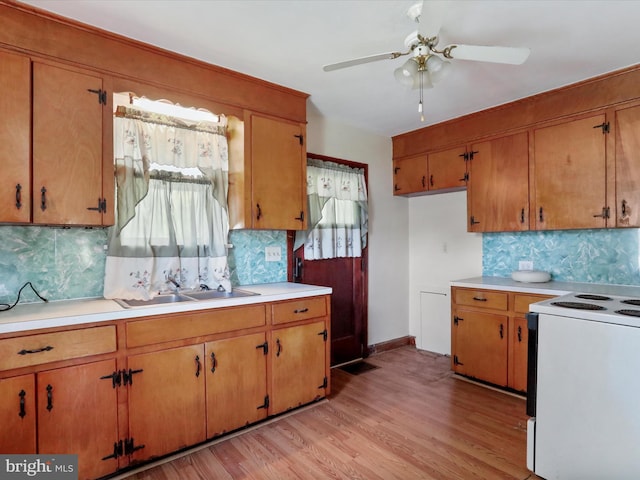 kitchen with light wood-type flooring, electric range, tasteful backsplash, and sink