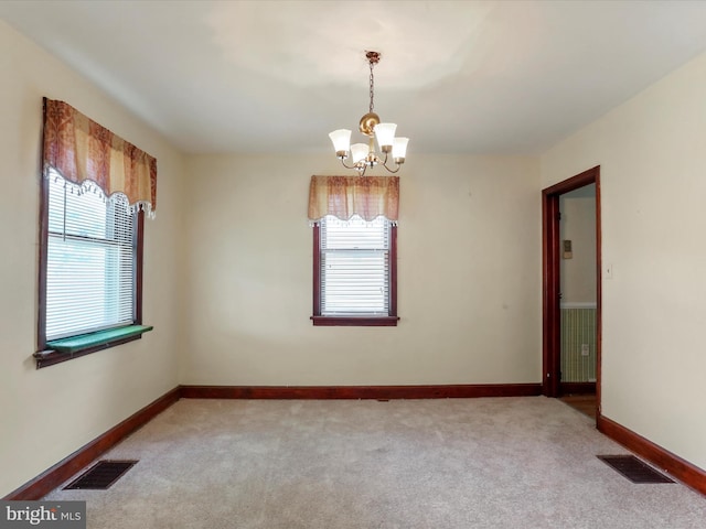 empty room with a notable chandelier, a healthy amount of sunlight, and light carpet