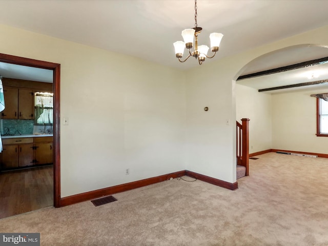 unfurnished room with beam ceiling, light colored carpet, and a notable chandelier