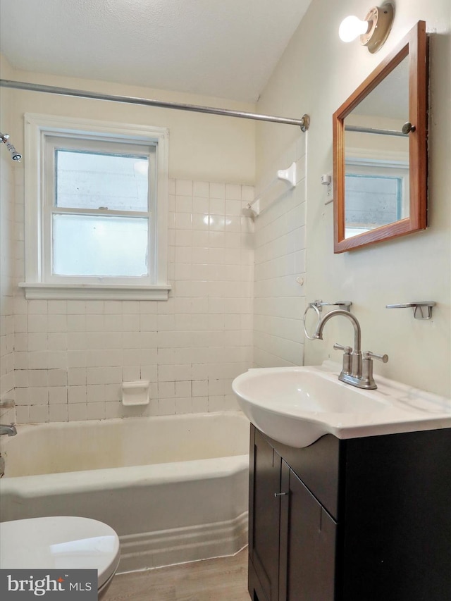 full bathroom featuring toilet, hardwood / wood-style floors, vanity, and tiled shower / bath combo