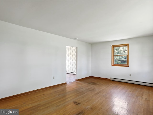 unfurnished room featuring wood-type flooring and a baseboard radiator