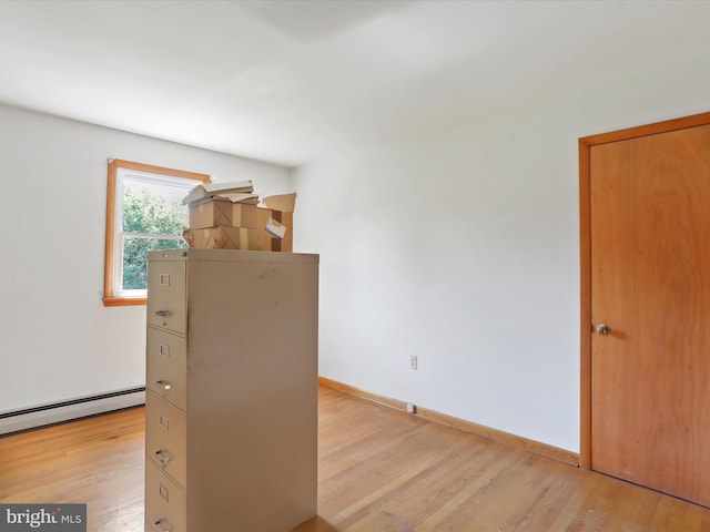 empty room with light hardwood / wood-style floors and a baseboard radiator