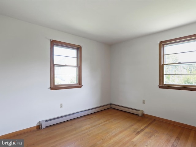 unfurnished room with light hardwood / wood-style flooring, a wealth of natural light, and a baseboard heating unit