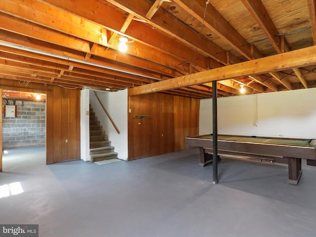 basement featuring electric panel and wood walls