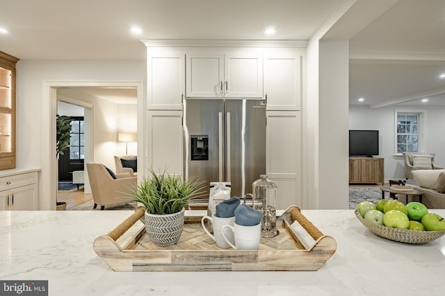 kitchen featuring white cabinetry, light stone counters, and stainless steel refrigerator with ice dispenser