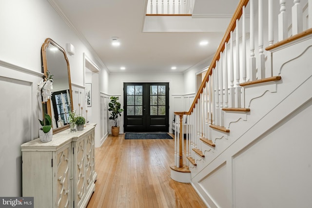 entryway with crown molding, french doors, and light hardwood / wood-style floors