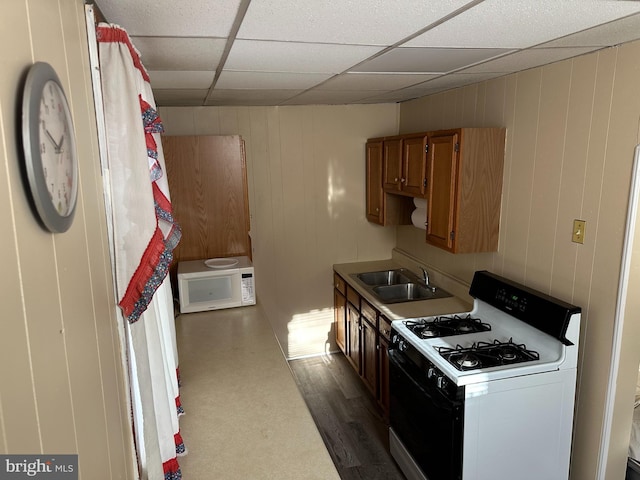 kitchen featuring a paneled ceiling, white gas stove, dark hardwood / wood-style flooring, and sink