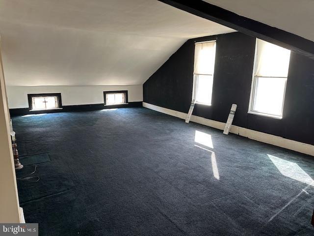 bonus room featuring vaulted ceiling and dark carpet