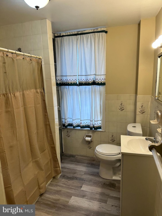 bathroom with a shower with shower curtain, vanity, hardwood / wood-style flooring, tile walls, and toilet