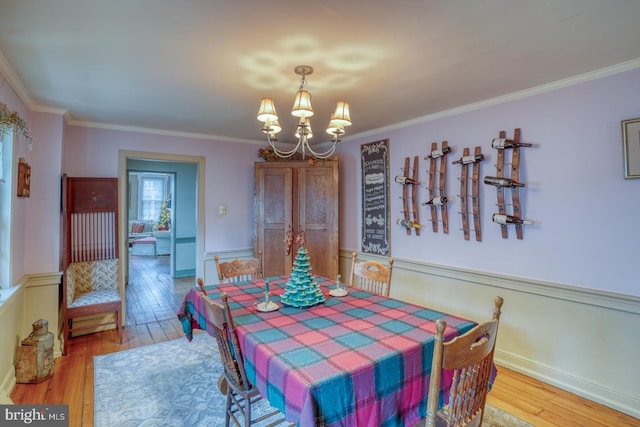 dining room with hardwood / wood-style floors, ornamental molding, and a notable chandelier