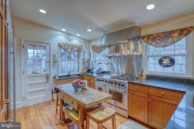 kitchen with island range hood, light wood-type flooring, backsplash, and stainless steel range