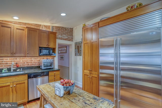 kitchen with light stone counters, sink, light hardwood / wood-style floors, and appliances with stainless steel finishes