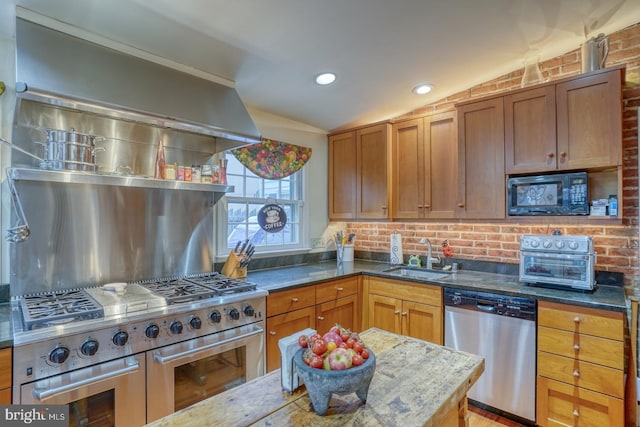 kitchen featuring lofted ceiling, backsplash, sink, dark stone countertops, and appliances with stainless steel finishes