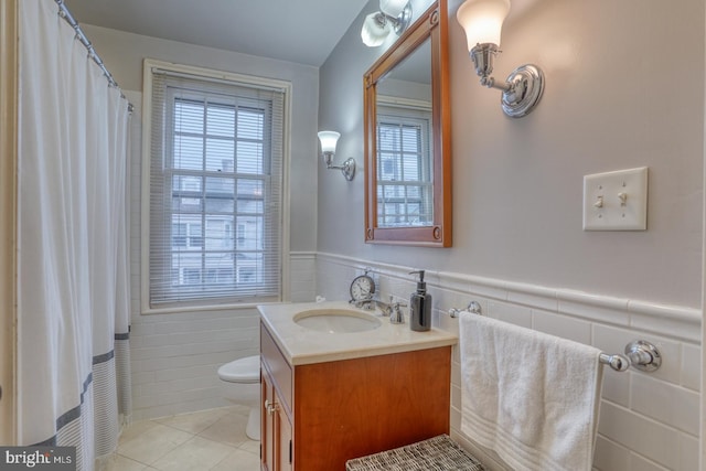 bathroom featuring tile patterned floors, vanity, toilet, and tile walls