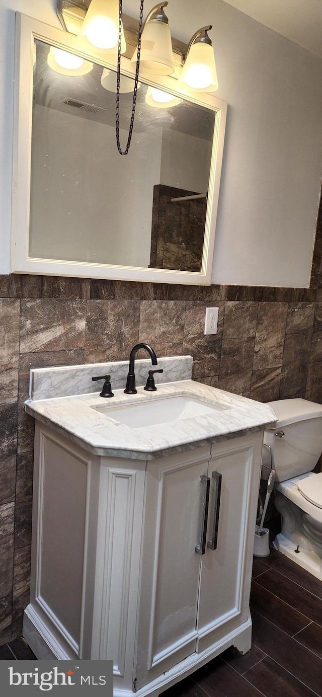 bathroom with vanity, toilet, and tile walls