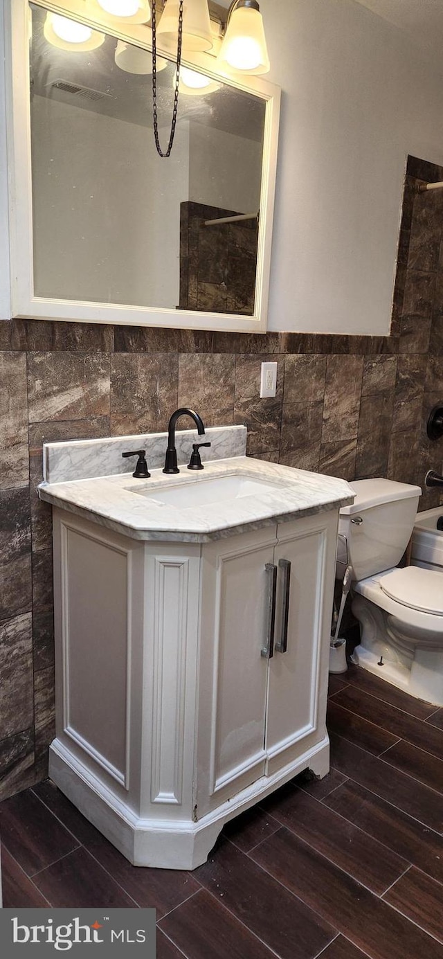 bathroom with vanity, toilet, and tile walls