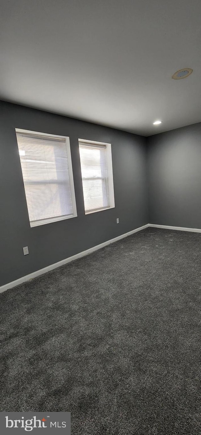 unfurnished room featuring dark colored carpet