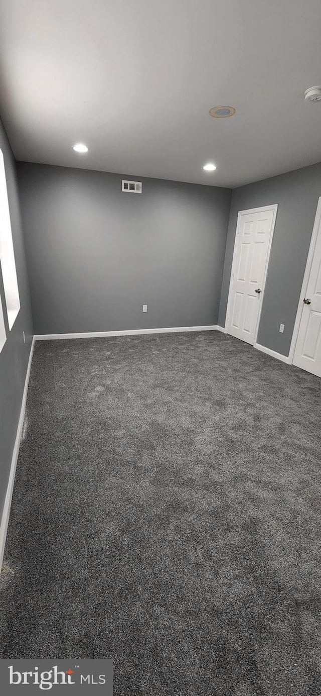 unfurnished room featuring dark carpet