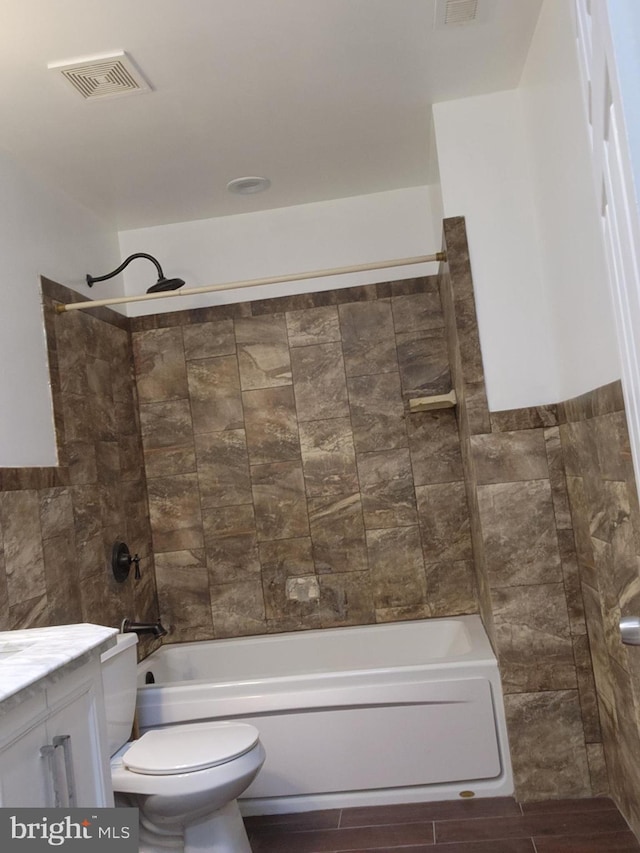 full bathroom featuring vanity, toilet, tiled shower / bath, and tile walls