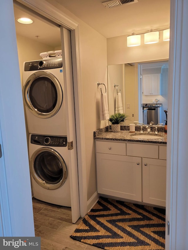 laundry area with stacked washer / dryer and sink