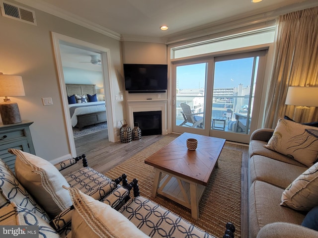 living room featuring crown molding, light hardwood / wood-style flooring, and ceiling fan