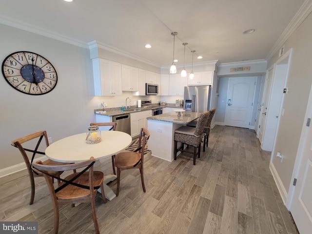 dining space with sink, light hardwood / wood-style flooring, and ornamental molding