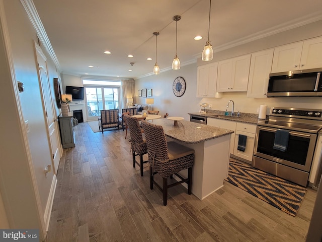 kitchen with a kitchen breakfast bar, sink, a kitchen island, white cabinetry, and stainless steel appliances