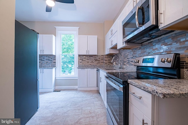 kitchen featuring light stone countertops, tasteful backsplash, stainless steel appliances, sink, and white cabinetry