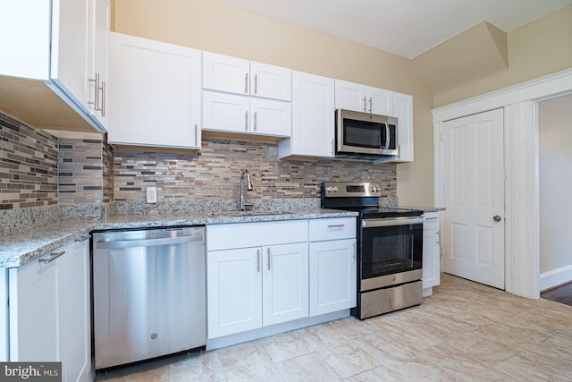 kitchen with white cabinets, appliances with stainless steel finishes, light stone counters, and sink