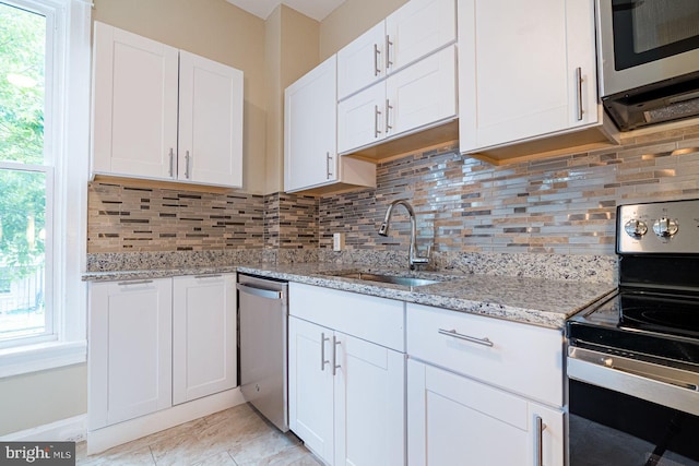 kitchen with white cabinets, sink, decorative backsplash, light stone countertops, and appliances with stainless steel finishes