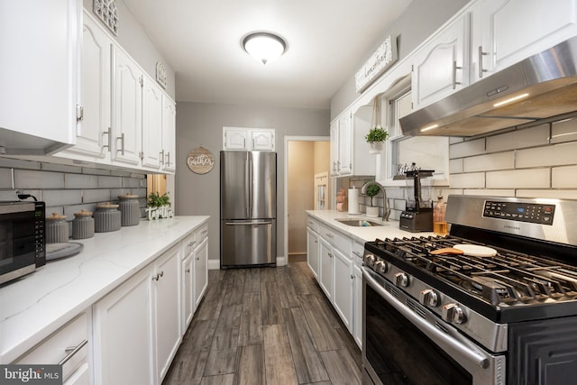 kitchen featuring appliances with stainless steel finishes, dark hardwood / wood-style flooring, white cabinetry, and light stone counters