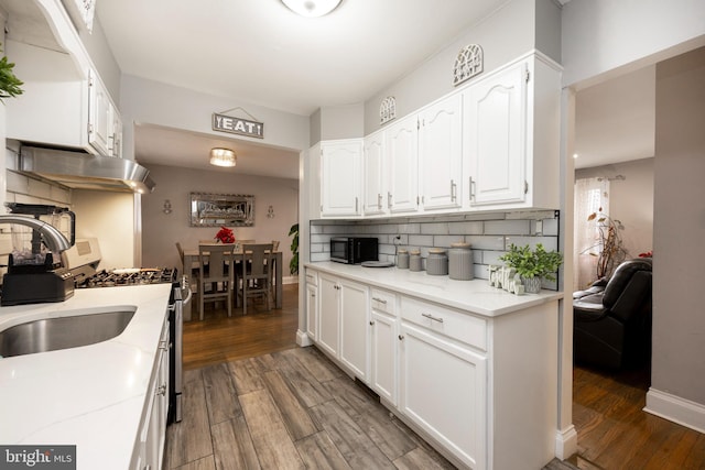 kitchen featuring dark wood-type flooring, white cabinets, sink, white gas range oven, and tasteful backsplash