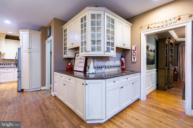 kitchen with stainless steel fridge, white cabinetry, and tasteful backsplash