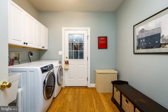 clothes washing area with washer and dryer, cabinets, and light hardwood / wood-style flooring