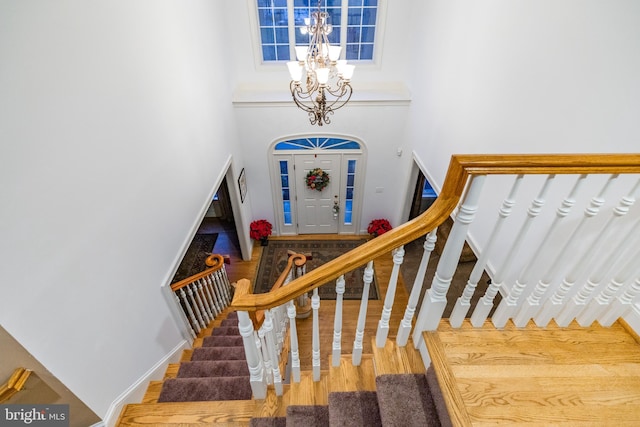 stairs with hardwood / wood-style floors, a high ceiling, and a notable chandelier