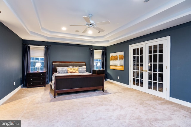 carpeted bedroom with a raised ceiling, ceiling fan, and french doors