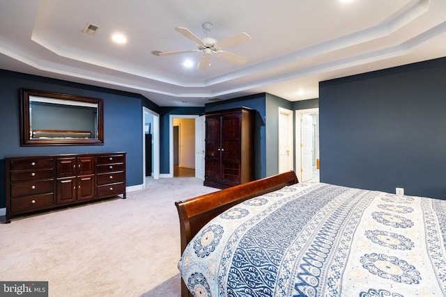 carpeted bedroom with ceiling fan and a raised ceiling