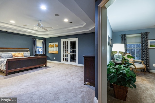 bedroom with a tray ceiling, ceiling fan, french doors, and carpet